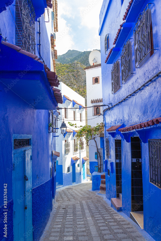 Empty narrow lane painted blue in medina of Chefchaouen town, Morocco. Traditional architecture for old town in North Africa.