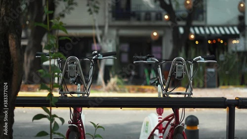 Two Public Bicycles Parked on the Street with a Blurry Building as Background