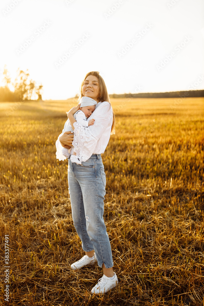 Pretty woman with cute newborn baby girl walking at the field, loving mother hold beautiful little daughter in arms, enjoy happy moments with child, maternity concept Pretty woman with cute newborn baby girl walking at the field, loving mother hold beautiful little daughter in arms, enjoy happy moments with child, maternity concept