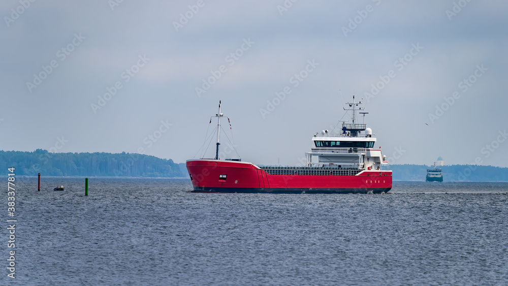 Traffic in the strait of Trangsund fairway from Vyborg port to Gulf of Finland with Vyborg castle and cityscape on background at overcast summer morning