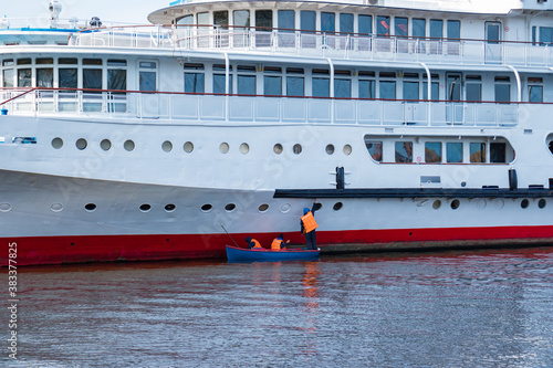 Boat with workers near the cruise ship, carrying out maintenance. © Igor Nikushin