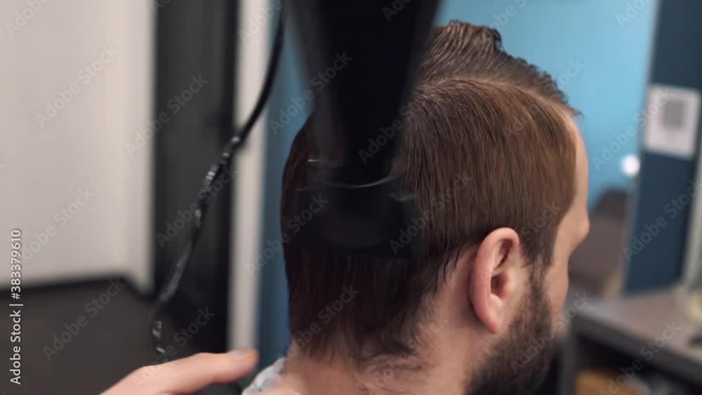 Barber blow-drying hair of a customer. Young man getting a modern haircut. Looking good already. Barber with hairdryer drying and styling hair of client. Barber with hairdryer. Visiting hair salon Barber blow-drying hair of a customer. Young man getting a modern haircut. Looking good already. Barber with hairdryer drying and styling hair of client. Barber with hairdryer. Visiting hair salon
