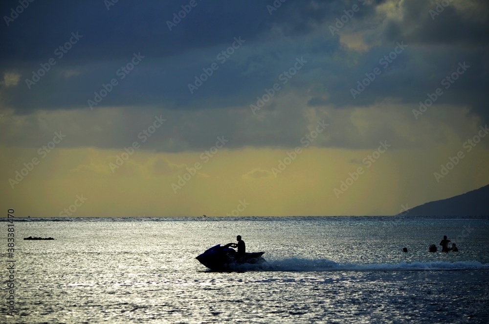 Un jetski nautique foil passe au coucher du soleil ciel d'orage sur le lagon Moorea et Tahiti à Punaauia