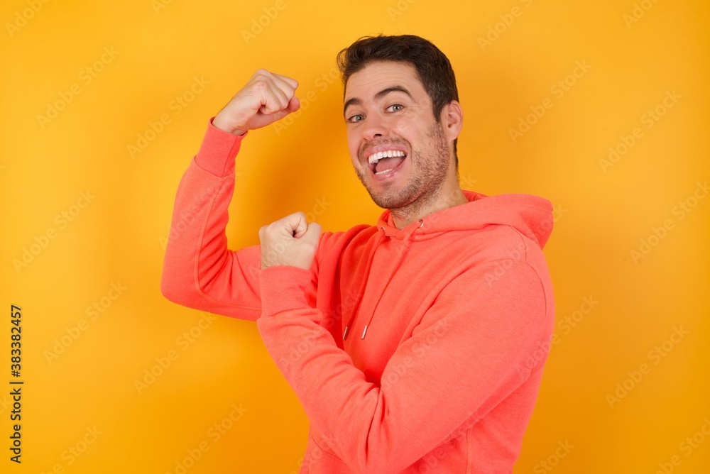 Profile photo of excited beautiful caucasian businessman wears red shirt isolated over yellow background raising fists celebrating black friday shopping Profile photo of excited beautiful caucasian businessman wears red shirt isolated over yellow background raising fists celebrating black friday shopping