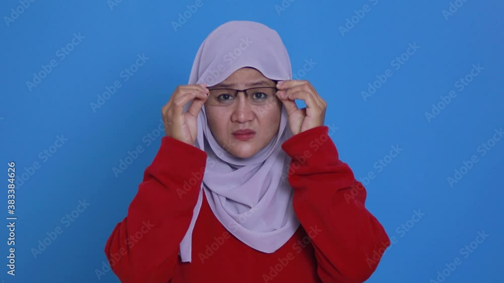 Portrait of Asian muslim woman adjusting her eyeglasses trying to see focus, eye sight trouble, blur vision Portrait of Asian muslim woman adjusting her eyeglasses trying to see focus, eye sight trouble, blur vision