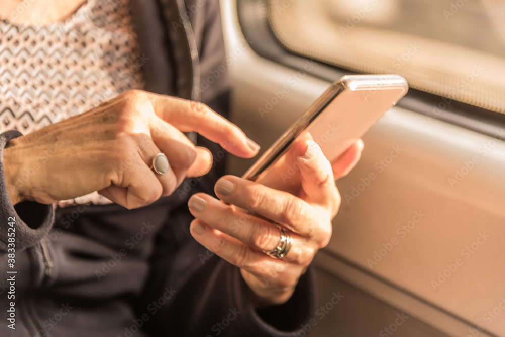 Adult woman's hands approaching writing a text on the mobile in the train Adult woman's hands approaching writing a text on the mobile in the train