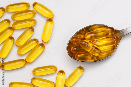 fish oil capsules in spoon on white background