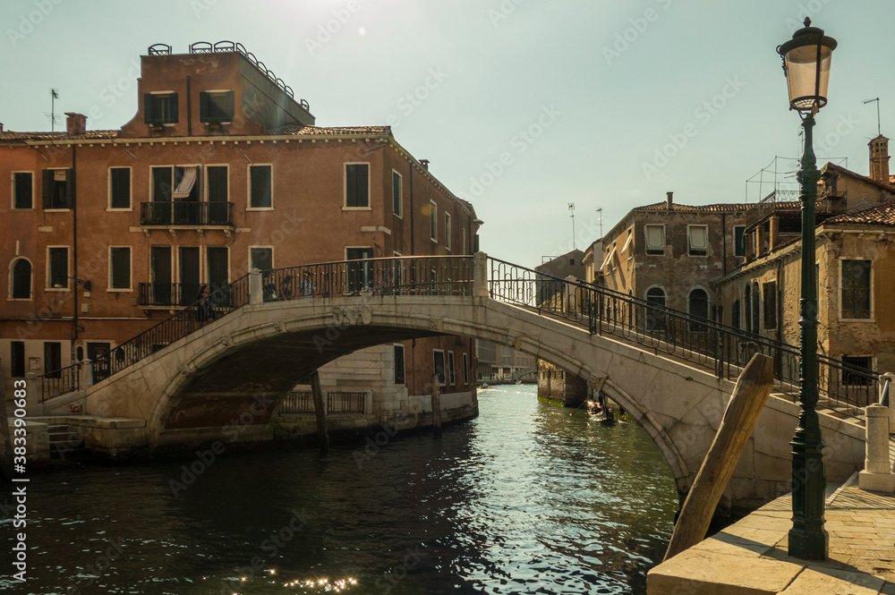 Venice bridge over canal with boat and blue sky in sunshine