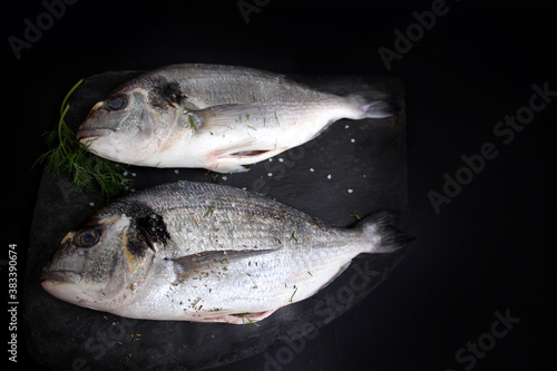 two pieces fresh raw atlantic sea fish lie on a black stone board, the concept of cooking seefood