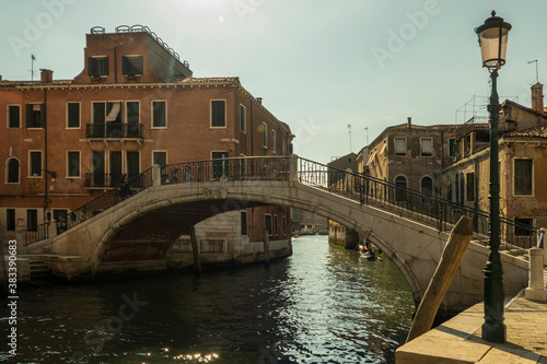 Venice bridge over canal with boat and blue sky in sunshine