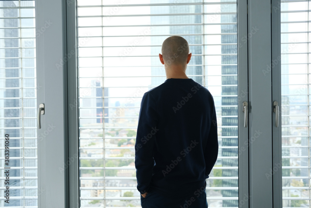 young man stands in an office in front of a window, looks at a modern European city, the concept of a business idea, a workplace young man stands in an office in front of a window, looks at a modern European city, the concept of a business idea, a workplace