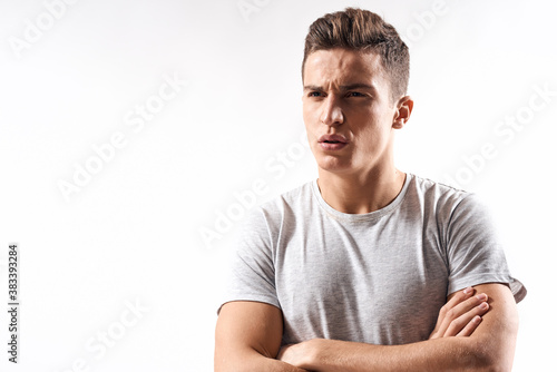 sporty man in white t-shirt on a light background gesturing with his hands cropped view Copy Space