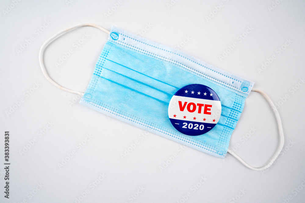 Face mask with american flag colored button with the text vote 2020..Voting, covid-19 and presidential election concept 2020. Face mask with american flag colored button with the text vote 2020..Voting, covid-19 and presidential election concept 2020.