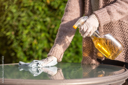 Mujer desinfectando con aspersor mesa de jardín, covid, sanitizar.