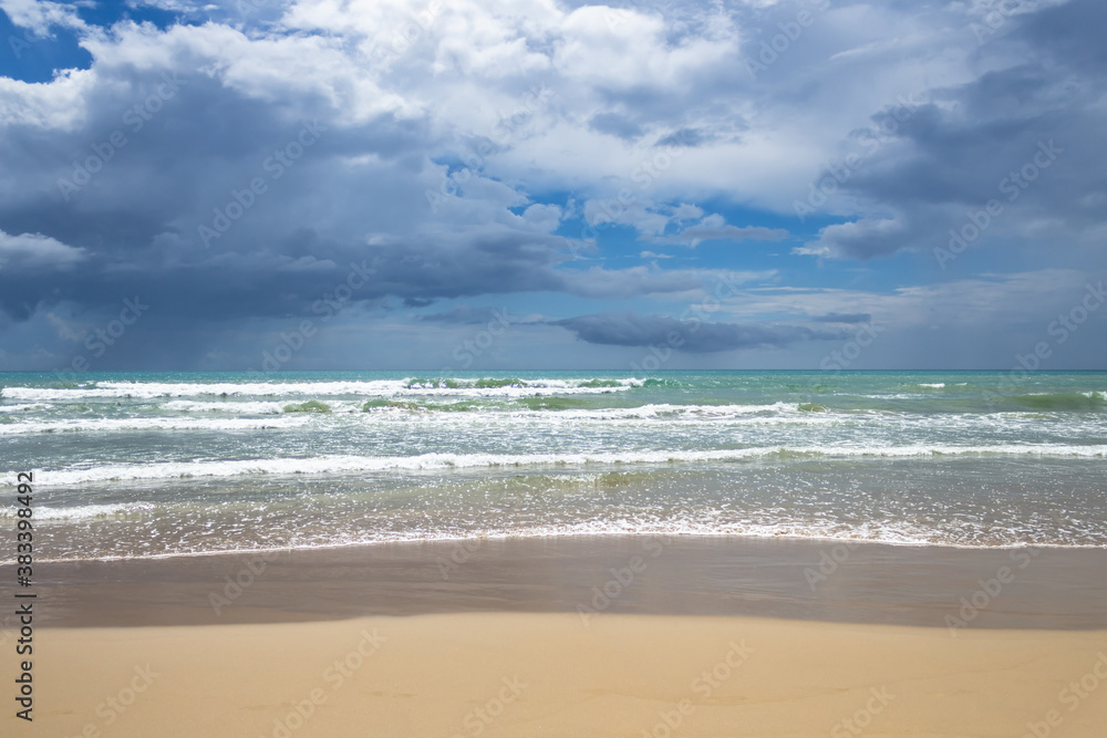 sandy beach and azure sea against blue sky with clouds