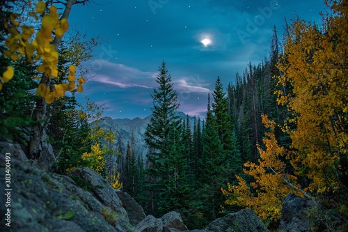 Mountain peak in Rocky Mountain National Park near Estes Park in Colorado. Taken in the evening of the night sky, fall leaves, stars, and moon.