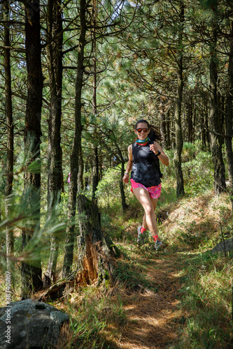 Atleta corriendo en un sendero de la montaña rodeada de arboles