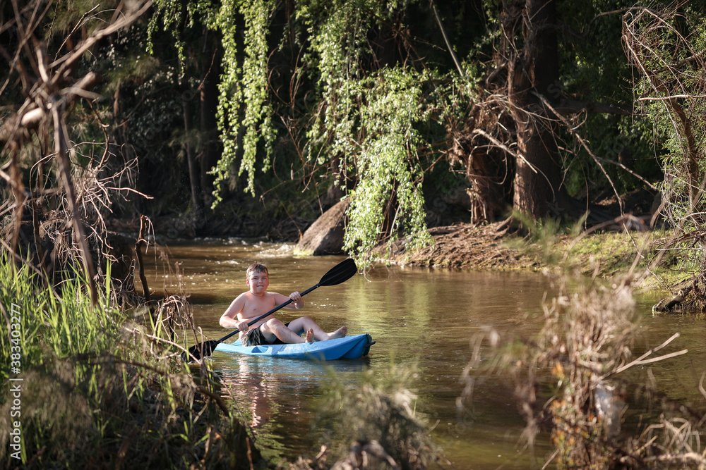 Young caucasion boy kayaking in river 