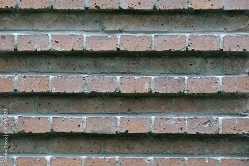 Photo of a fragment of a brick wall. Masonry with relief stripes. In gray and red tones.