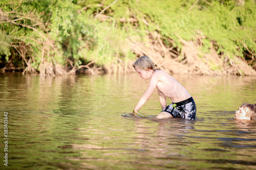 Fototapeta Naklejka Na Ścianę i Meble -  Boy swimming in fresh water river at dusk in New South Wales, Australia
