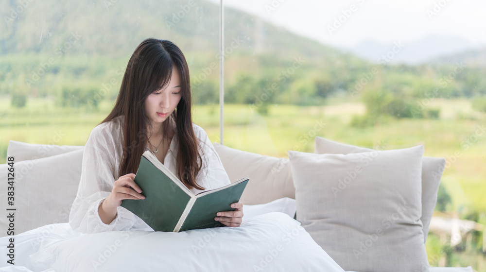 Obraz premium Young girls with long hair sitting on the bed reading a book