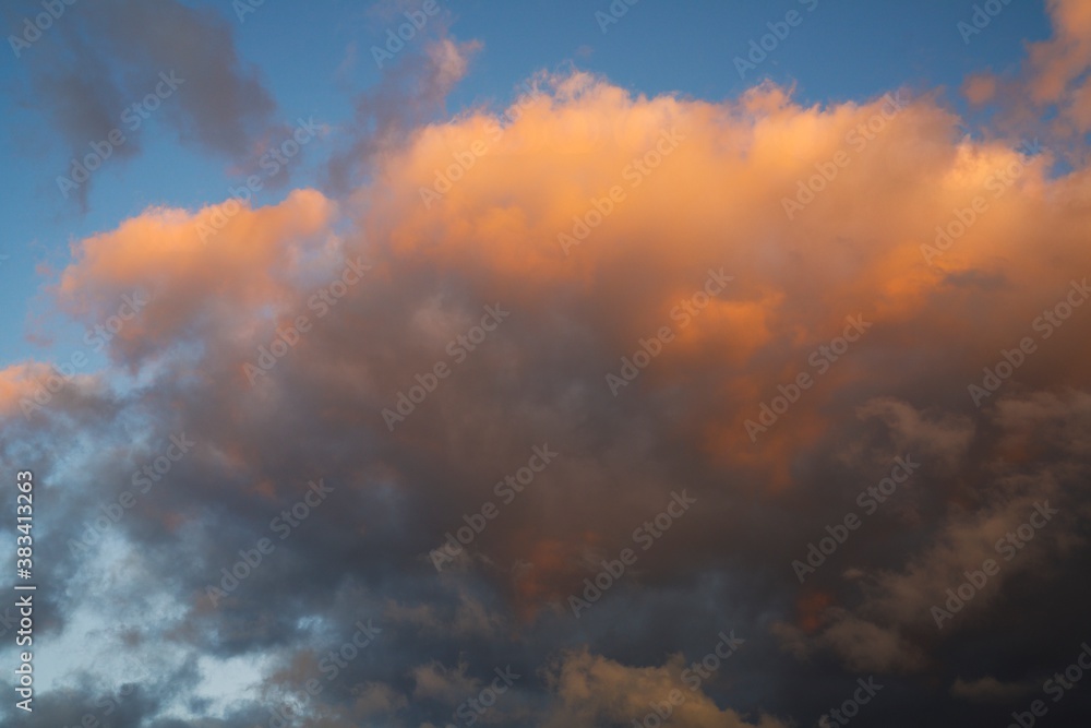 This whimsical image shows sunset colored clouds glowing in an early evening blue sky