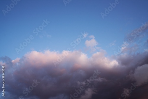 This dreamlike image features fluffy white clouds moving across a beautiful summer blue sky.