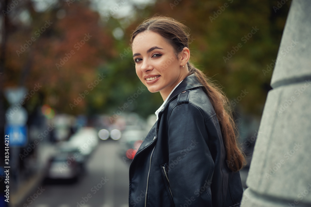 Young beautiful girl in a fashionable leather jacket on a city street
