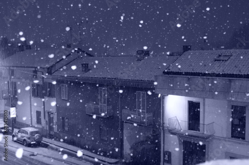 Snow falling over town houses in christmas season in Turin Italy Chivasso at night	

