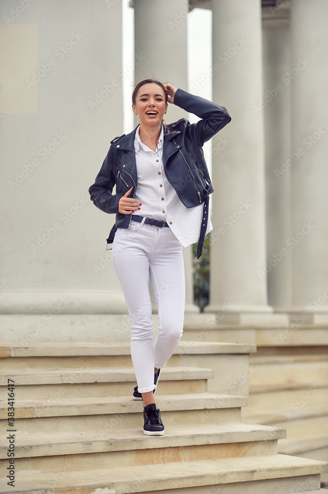 Young beautiful girl in a fashionable leather jacket on a city street
