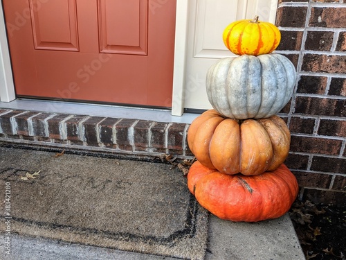 Colorful stack of pumpkins on front door step with welcome mat - Stacking Pumpkins