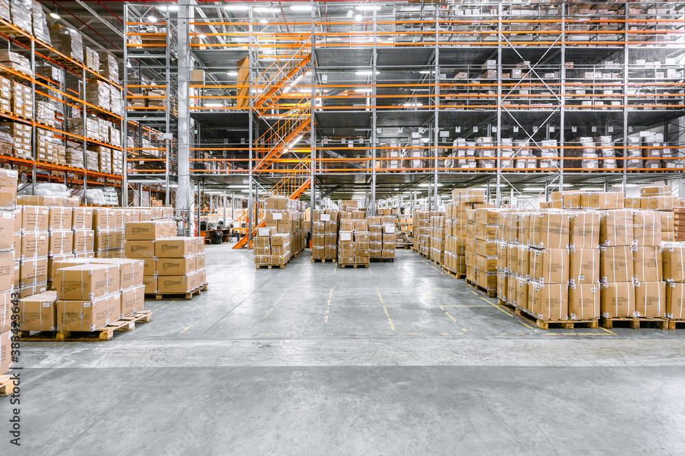 Large industrial warehouse. Tall racks are completely filled with boxes and containers.