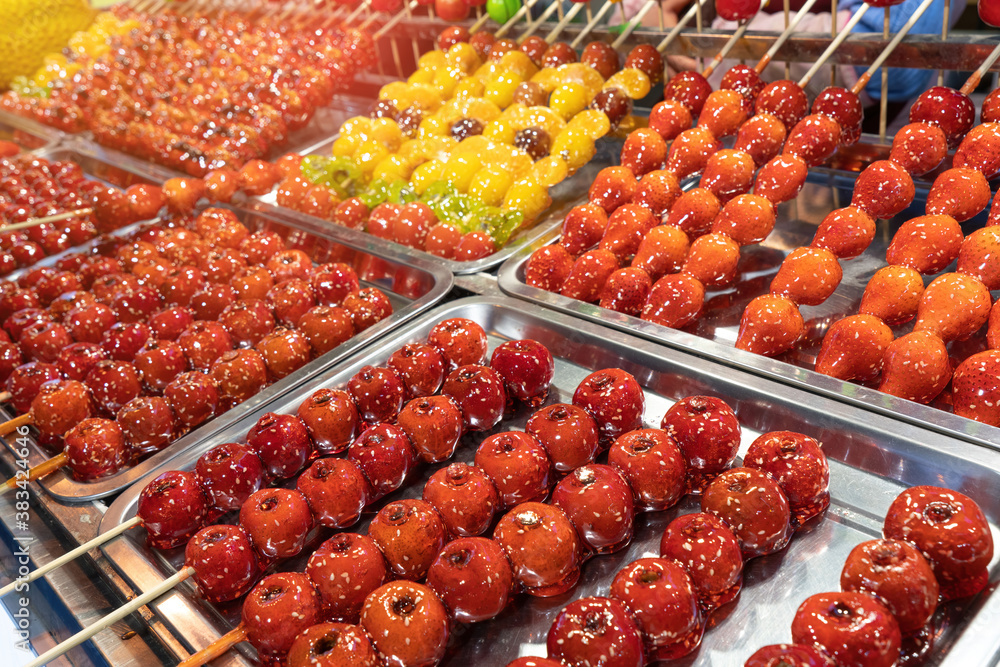 Tanghulu traditional Chinese dessert candied fruit on a wooden stick. Sugar candy Chinese dessert street food.