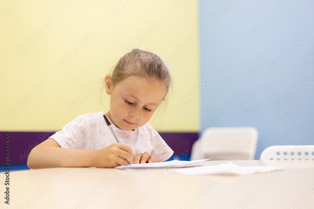 Young girl taking notes in class at school bending over his paperwork Young girl taking notes in class at school bending over his paperwork