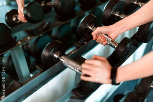 women hands lifting dumbbells workouts with dumbbells in a gym. Sport women at fitness gym.