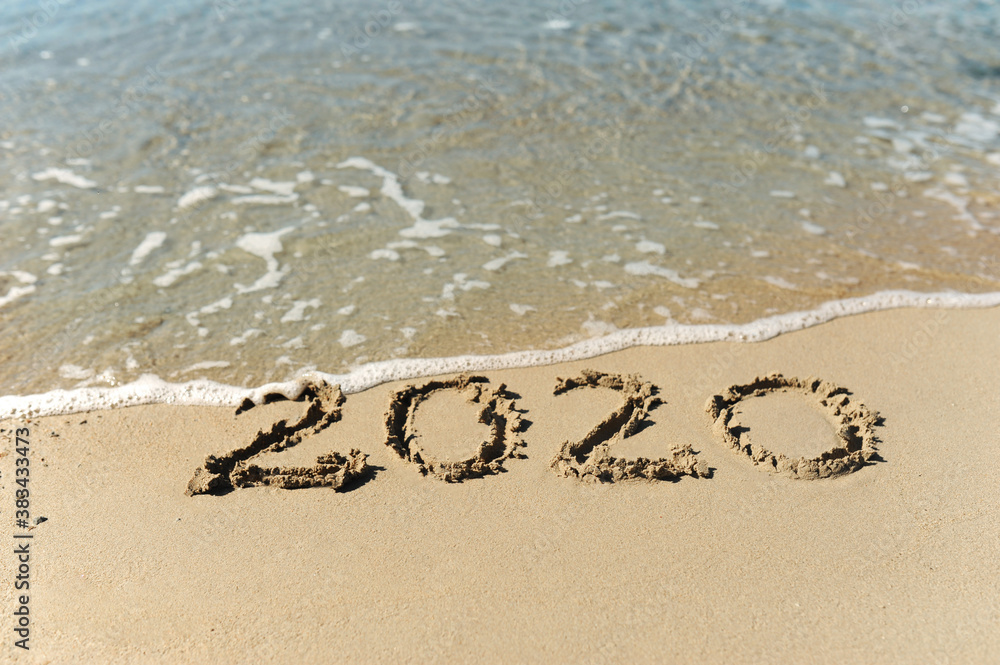 Fototapeta premium wave of clear blue clear sea water washes away the inscription on the sand 2020, selective focus