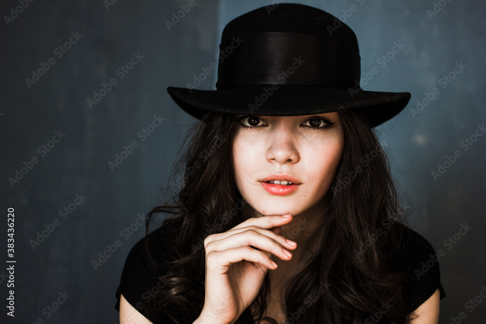 Portrait of beautiful brunette woman in hat, stylish girl posing on blue background
