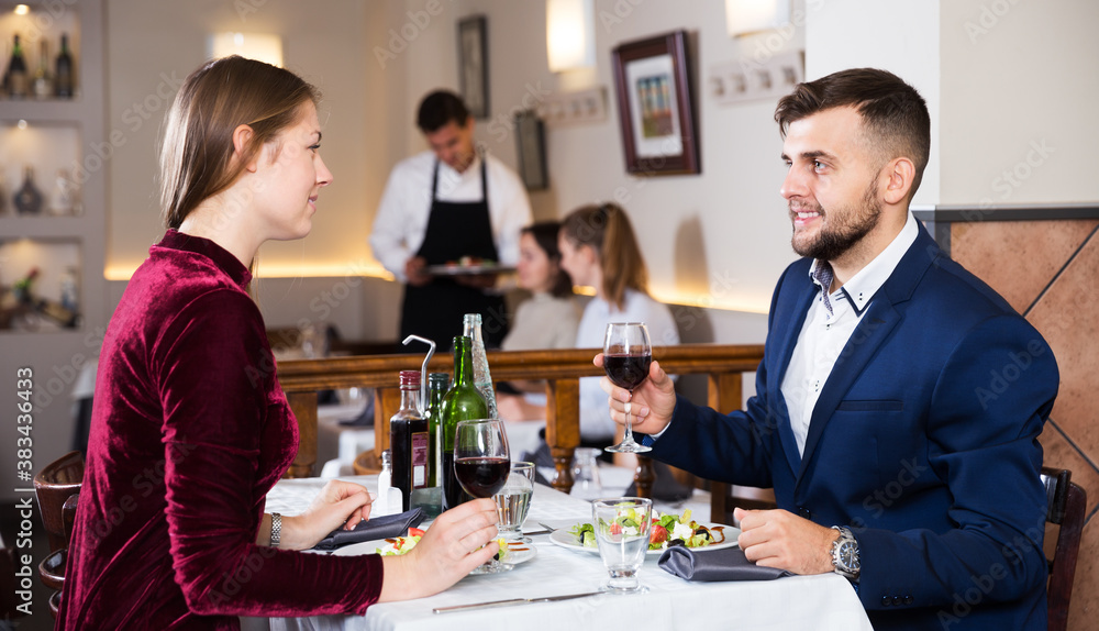 Elegant romantic couple enjoying wine on date at restaurant
