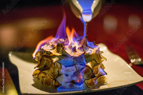 a burnt alaska or bombe alaska flambe on a plate with berries on the side
