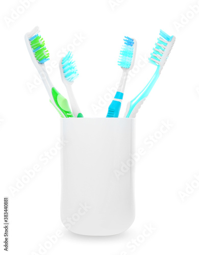 Cup with tooth brushes on white background