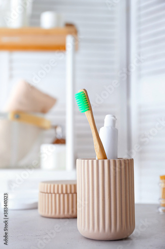 Cup with tooth brush and paste in bathroom