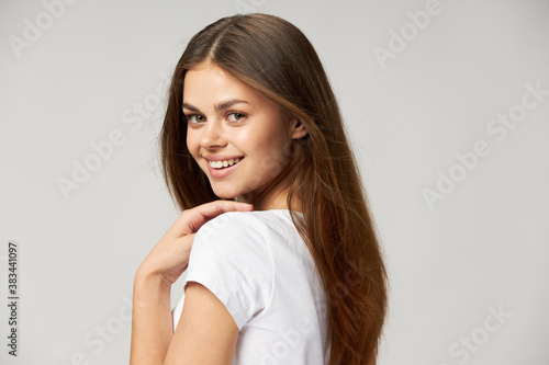 a nice woman with a beautiful smile in a white T-shirt on a light background and loose hair