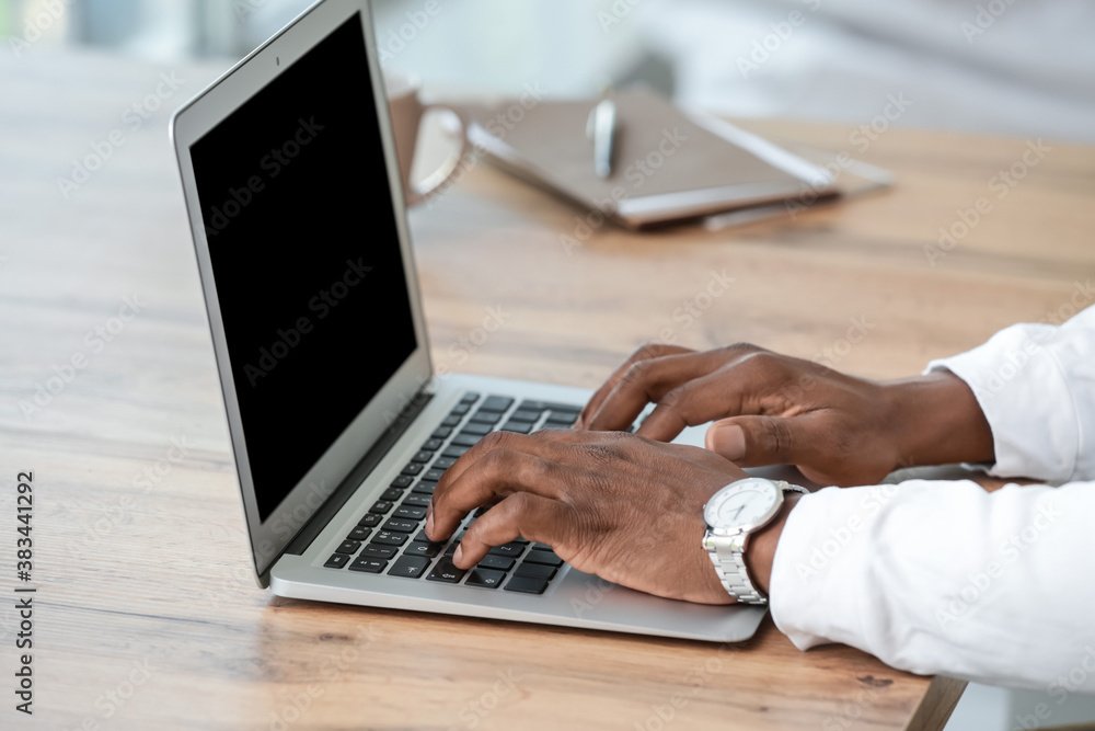 African-American man working on laptop in office, closeup African-American man working on laptop in office, closeup