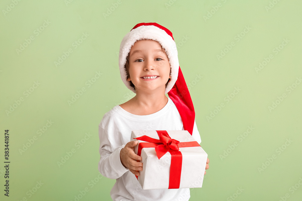 Cute little boy in Santa hat and with gift on color background Cute little boy in Santa hat and with gift on color background