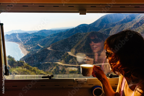 Woman in rv enjoy coast view, drinking coffee