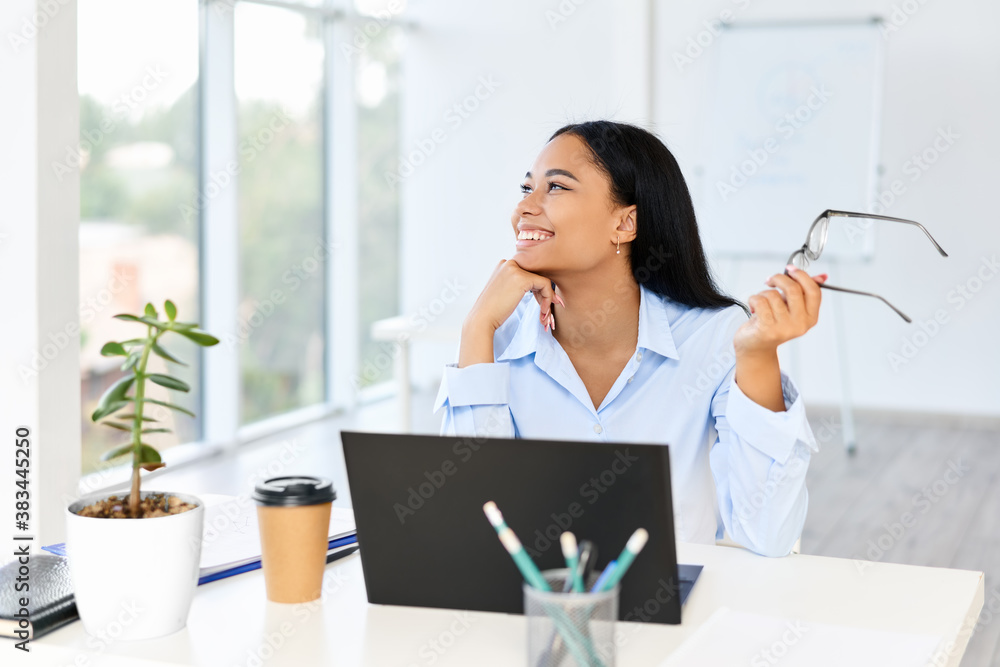 Smiling pretty businesswoman posing at her desk in a bright modern office with copy space Smiling pretty businesswoman posing at her desk in a bright modern office with copy space