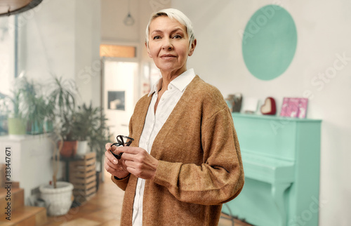 Фотография A mature well-dressed good looking woman with a short haircut and glasses in her