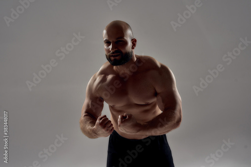 Muscular strong caucasian man bodybuilder showing his perfect body, chest, biceps, abs and looking aside while posing shirtless isolated over grey background