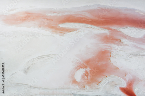 Natural background of the white surface of a salty reservoir with a pink abstract pattern due to algae blooming. Shooting from a drone.