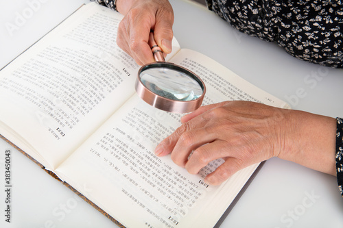 Фотография The elderly are reading books with a magnifying glass in hand